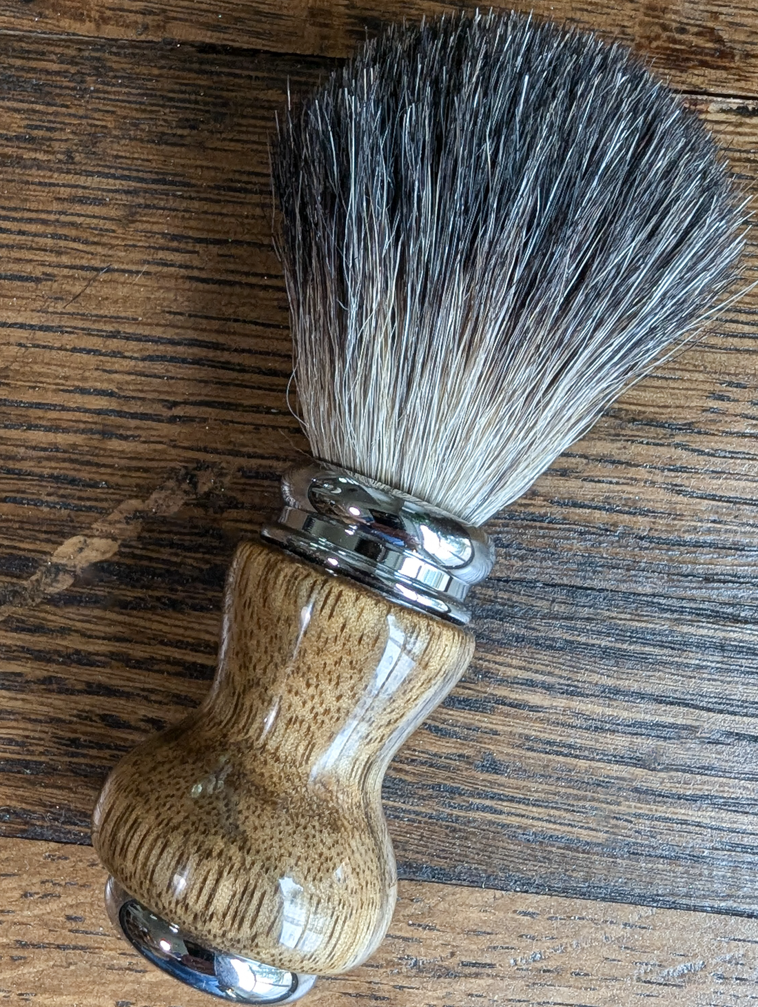 black badger shave brush with black limba handle on a bourbon barrel