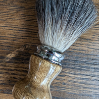 black badger shave brush with black limba handle on a bourbon barrel